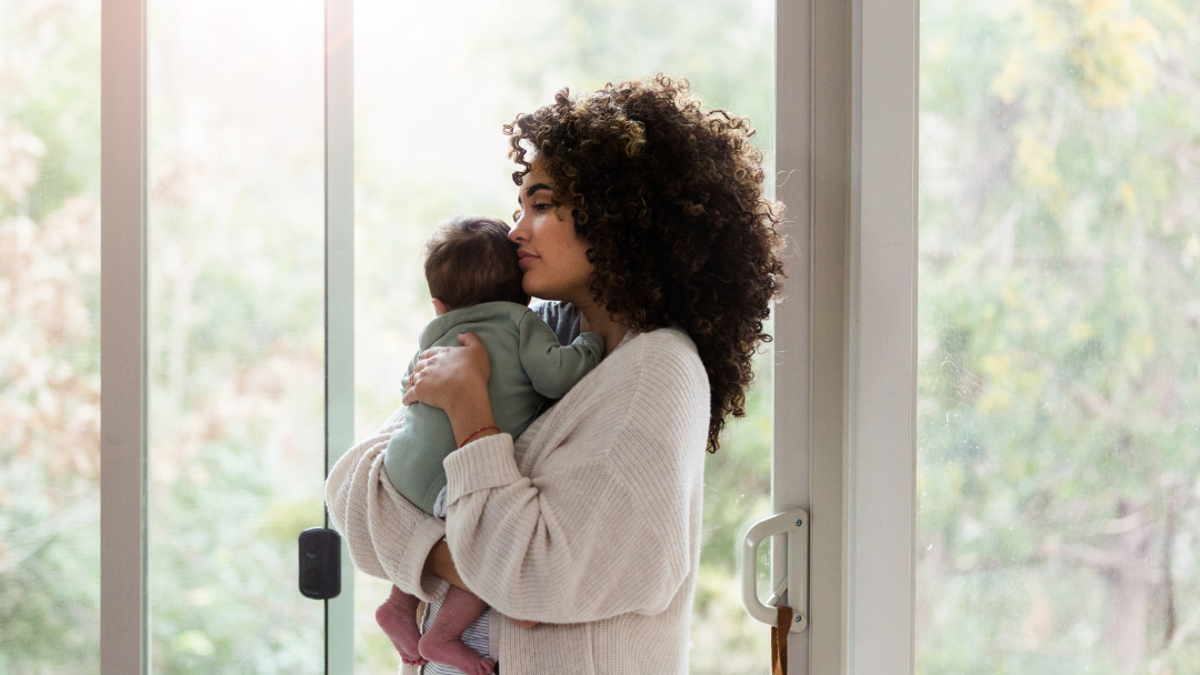 Mum holding baby by window